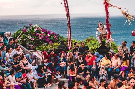 Colorful and lively traditional dance performance captivates a large outdoor audience by the sea.